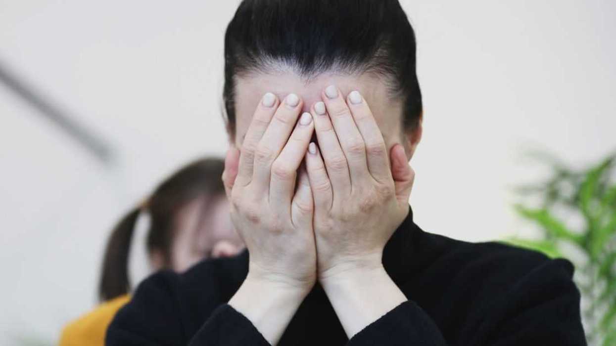 An upset woman cries into her hands