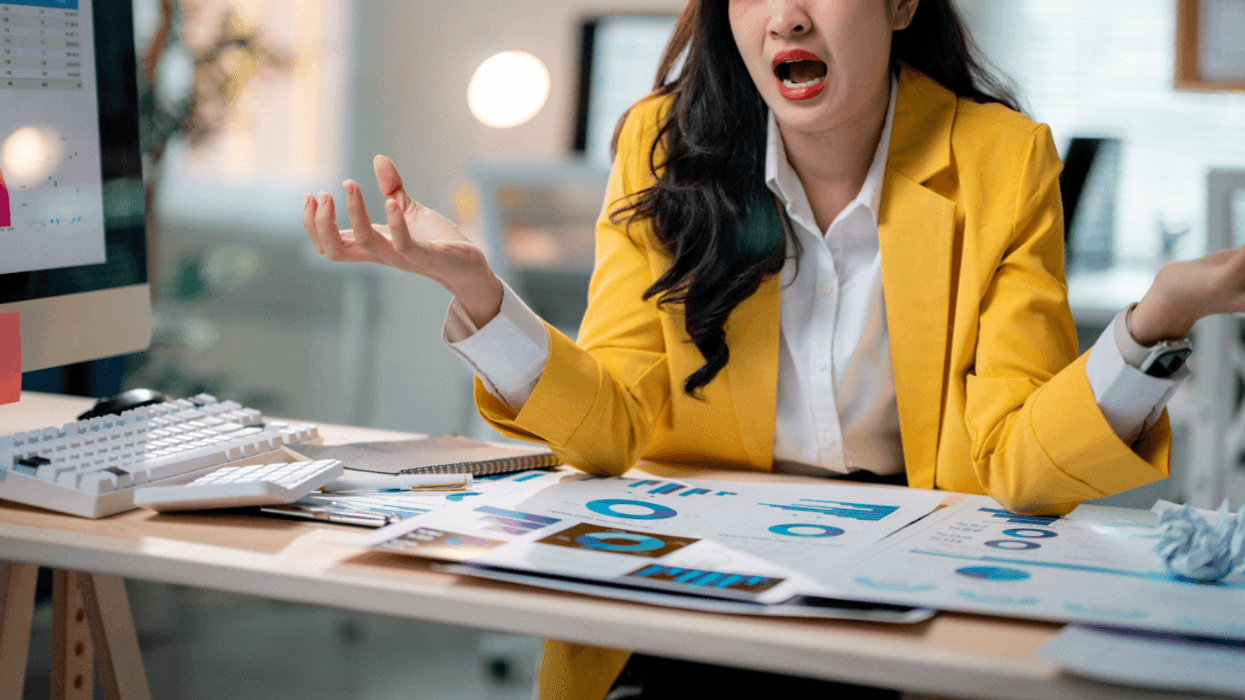 An woman sitting at a desk with a distressed expression on her face.