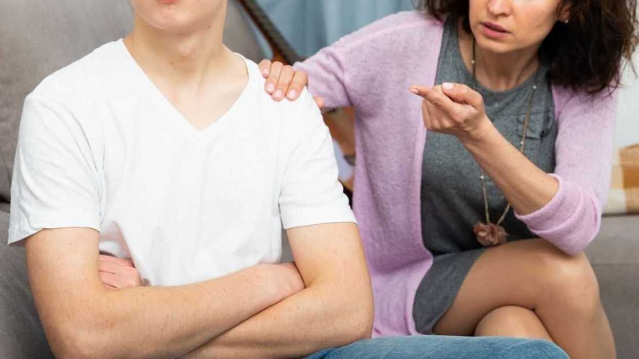 Annoyed mother discussing misbehavior with teenage son at home.