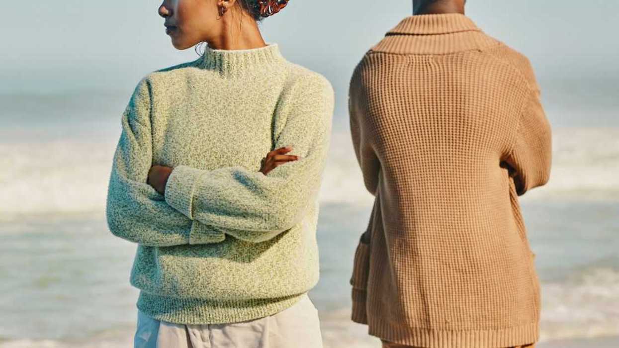 At the beach, upset, unhappy and angry man and woman ignoring each other after a fight, arguing or quarrel