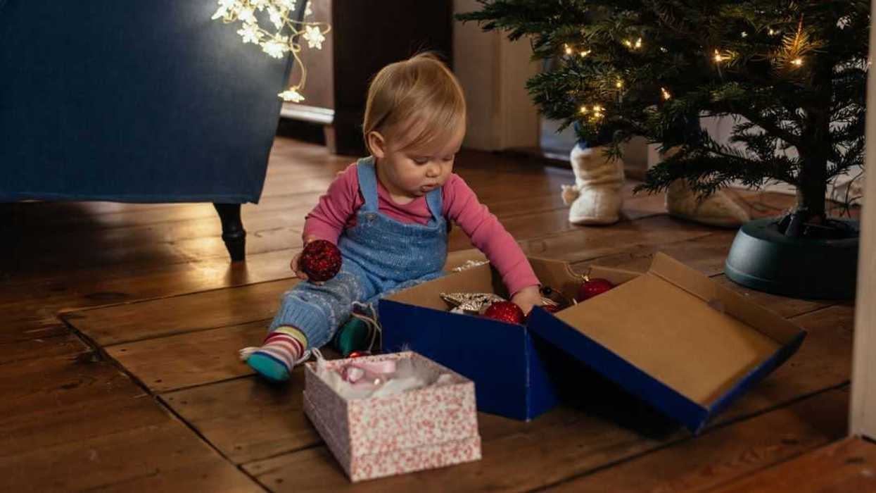 Baby girl looking at christmas decoration in front of christmas tree.