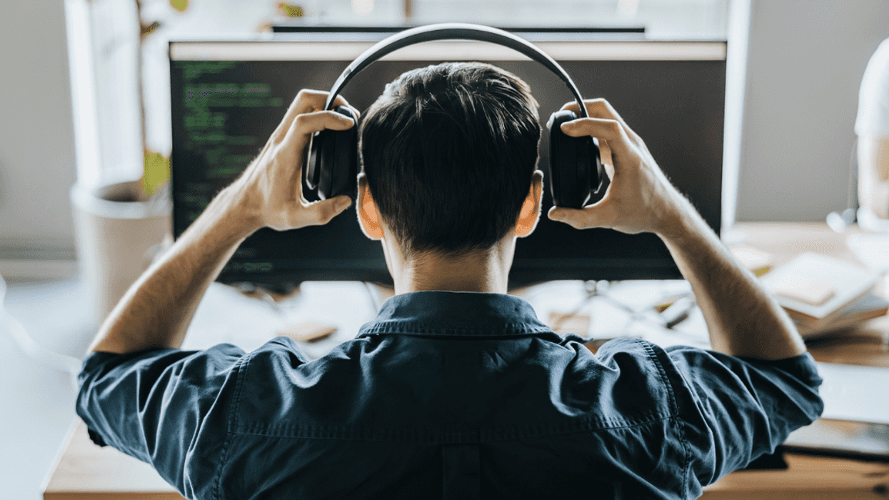 back of seated man's head as he puts on headphones