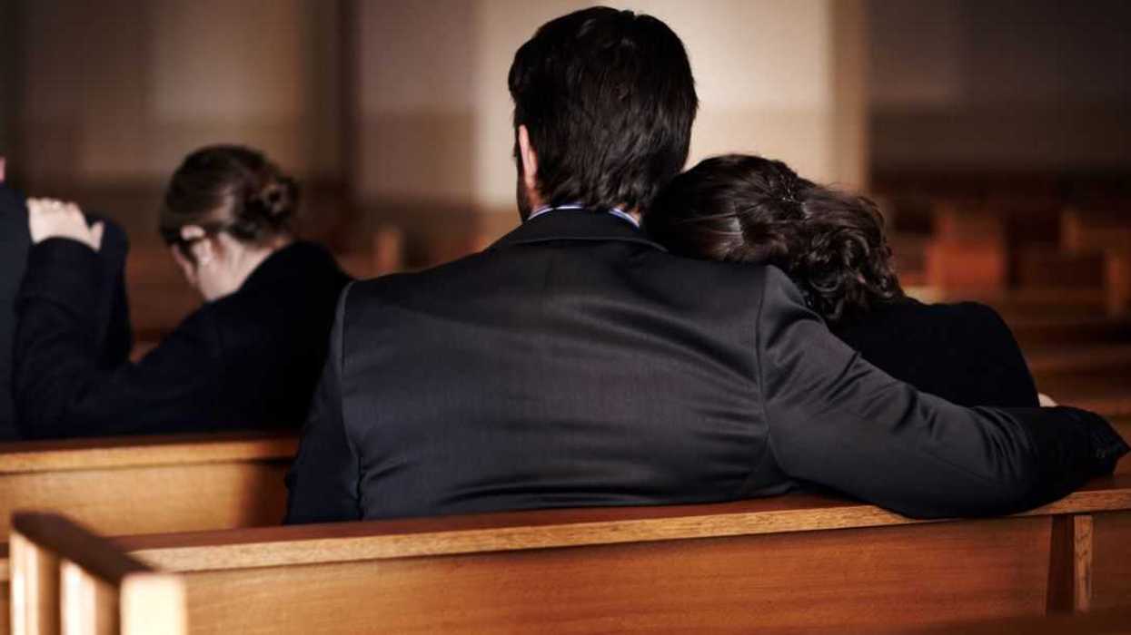 Back shot of people consoling one another at a funeral.