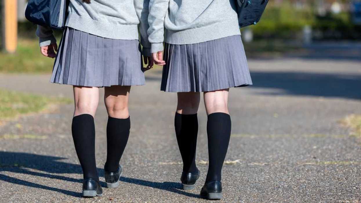 Back shot of two unrecognizable school girls walking.