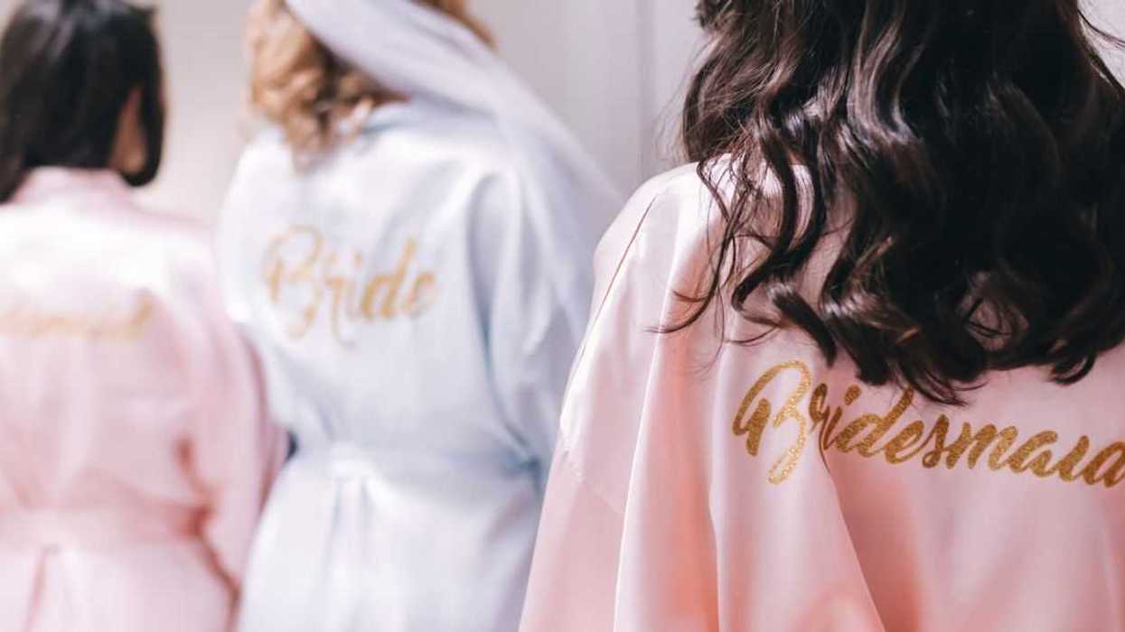 Back view of a group of bridesmaids with the bride-to-be in beautiful silk robes with different names on the back.