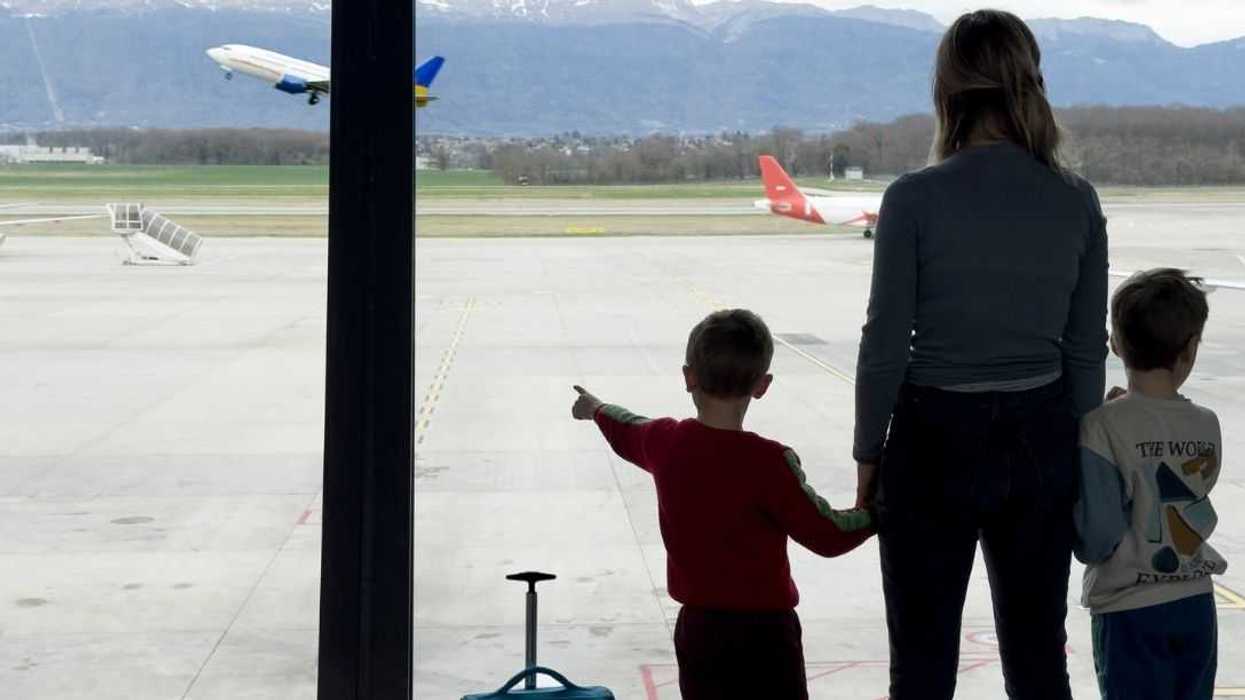 Backview shot of a family of three at airport looking at an aircraft taking off.