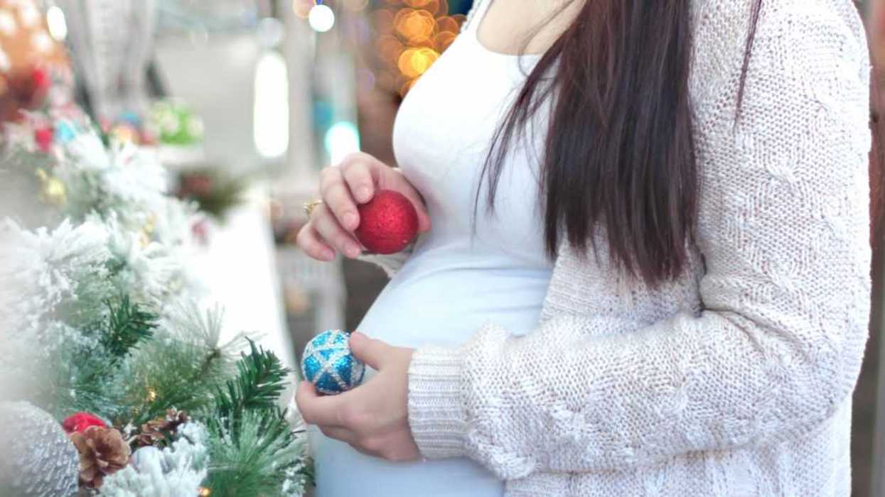Belly of a pregnant woman hanging Christmas balls.