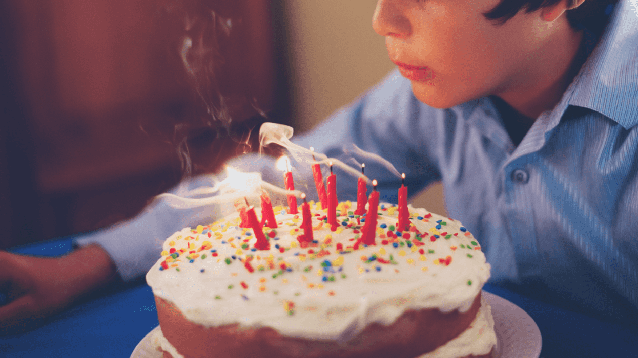 boy blowing out candles on birthday cake