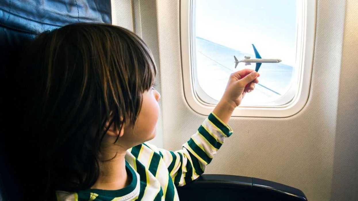 Boy playing with toy airplane at airplane window.