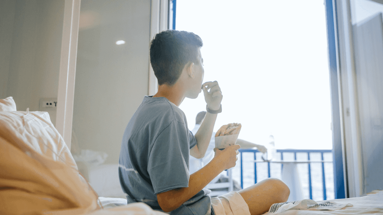 Boy sitting on his bed and eating alone.