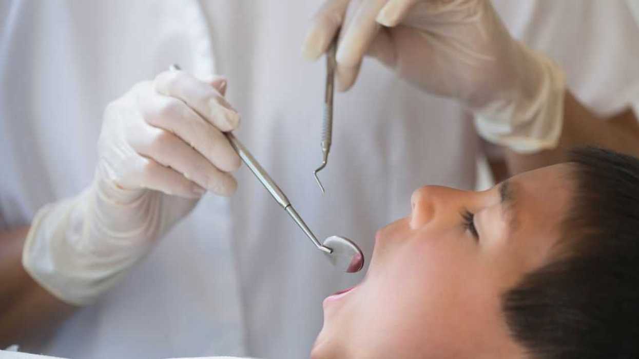 Boy with mouth open being examined by dentist.