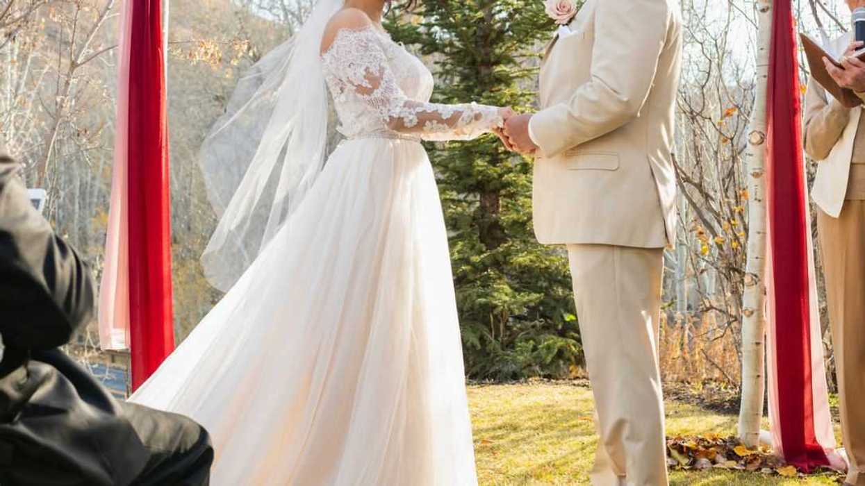 Bride and groom being married in outdoor ceremony .