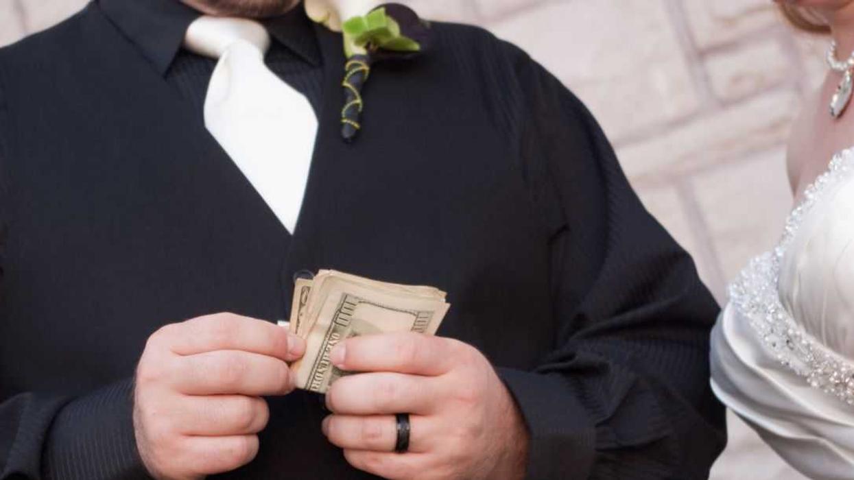 Bride and groom close up on the groom's hands holding American bills.
