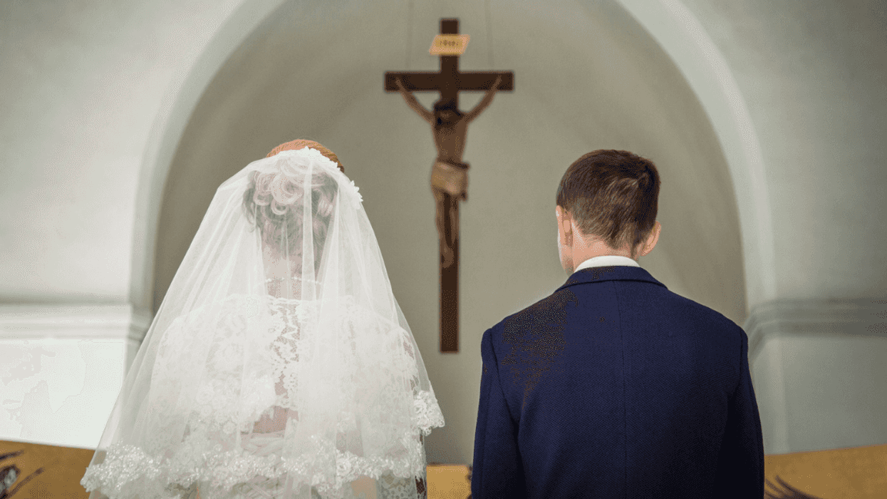 bride and groom kneeling in church before a rood
