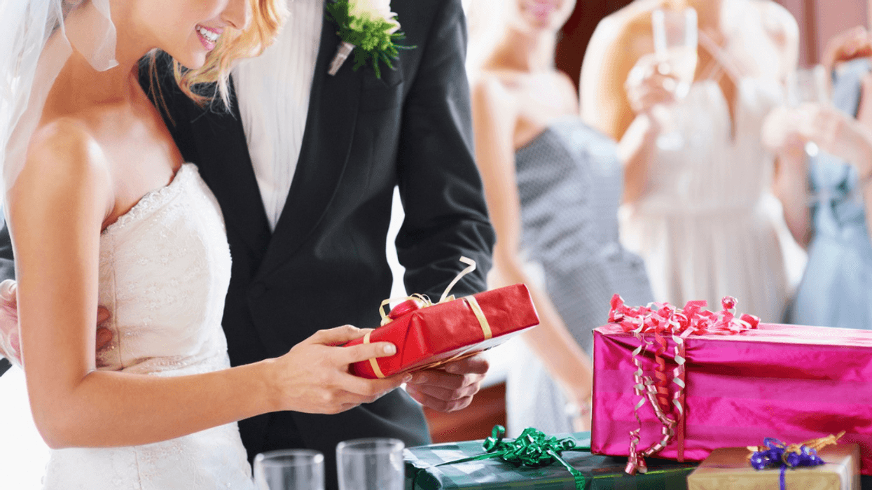 bride and groom look at wedding gifts as others look on