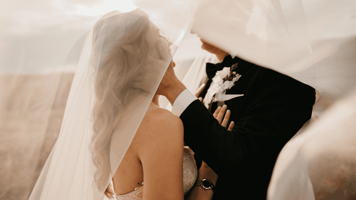 Bride and groom taking photos under the bride's wedding veil