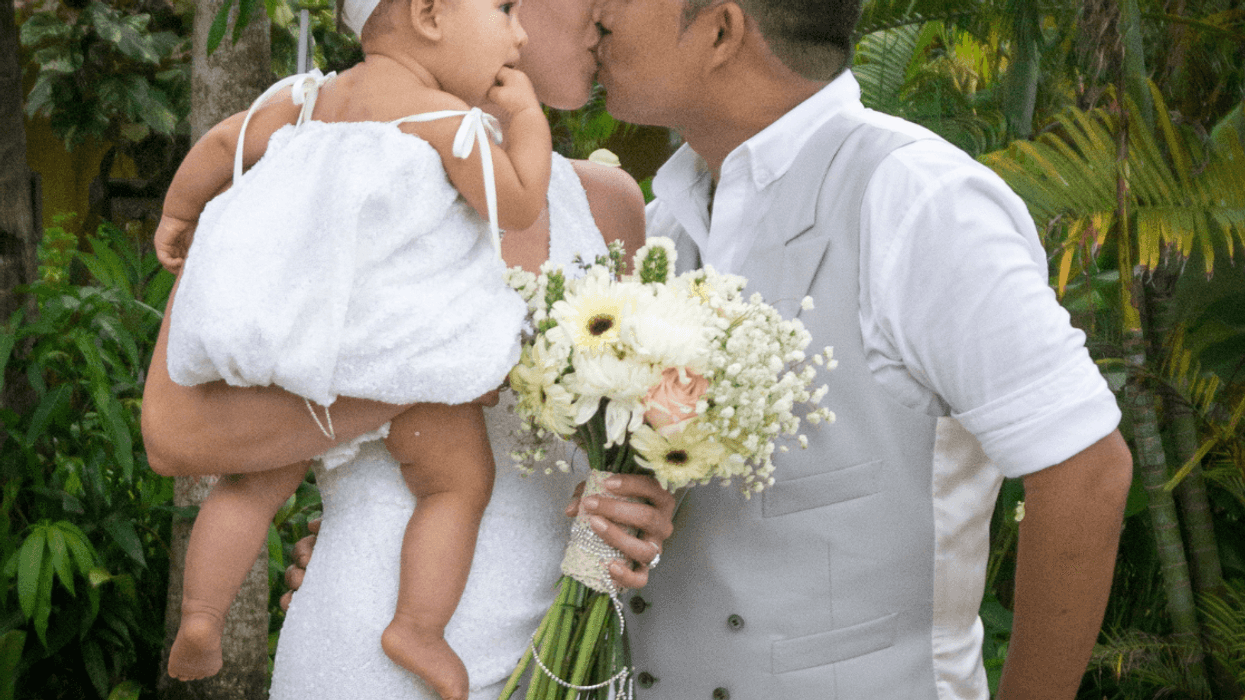 Bride and groom with young daughter at wedding
