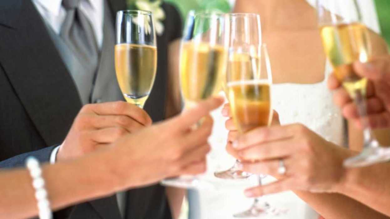 Bride, groom and wedding guests toasting with champagne, mid section.