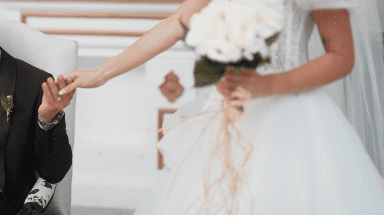 bride reaching out to seated groom
