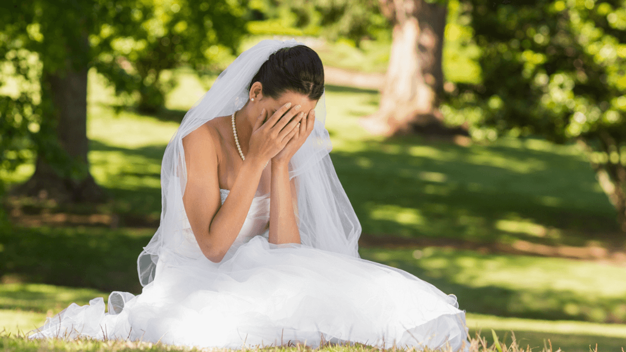 Bride sitting on the ground and crying.