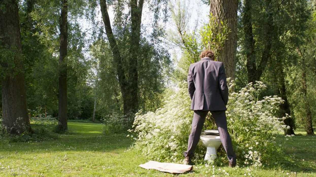 Businessman using a bush as a toilet in a park.