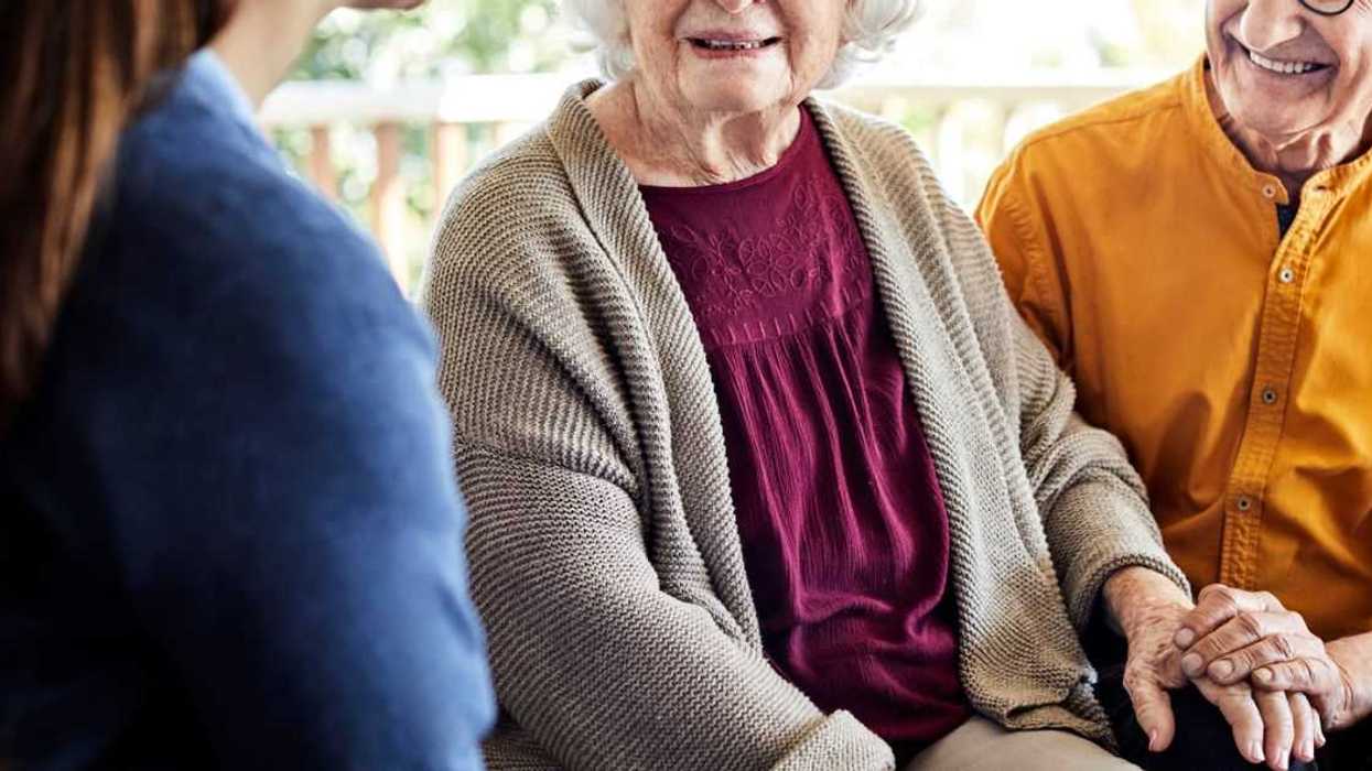 Caregiver with happy senior couple. Smiling elderly male and female are with nurse at home. They are on a home balcony home.