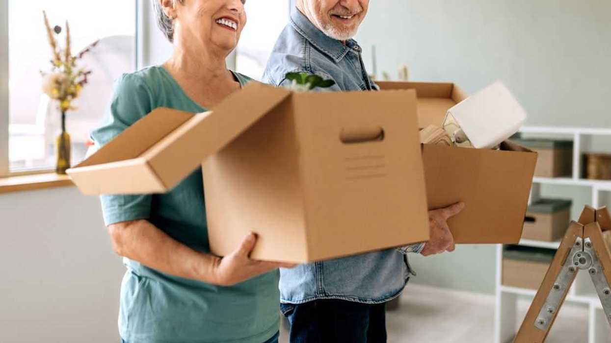Casually clothed senior couple with belongings in cardboard boxes at their freshly renovated home.