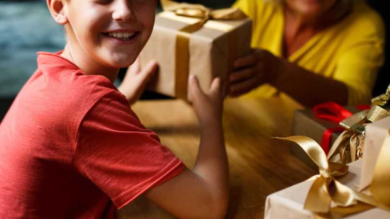 Cheerful boy, elementary age is getting presents from his granny.