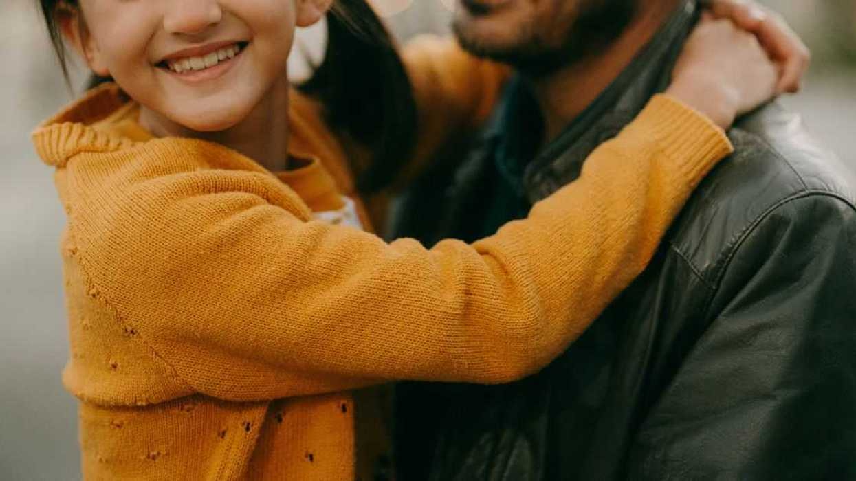 Cheerful young girl and her father embracing at dusk