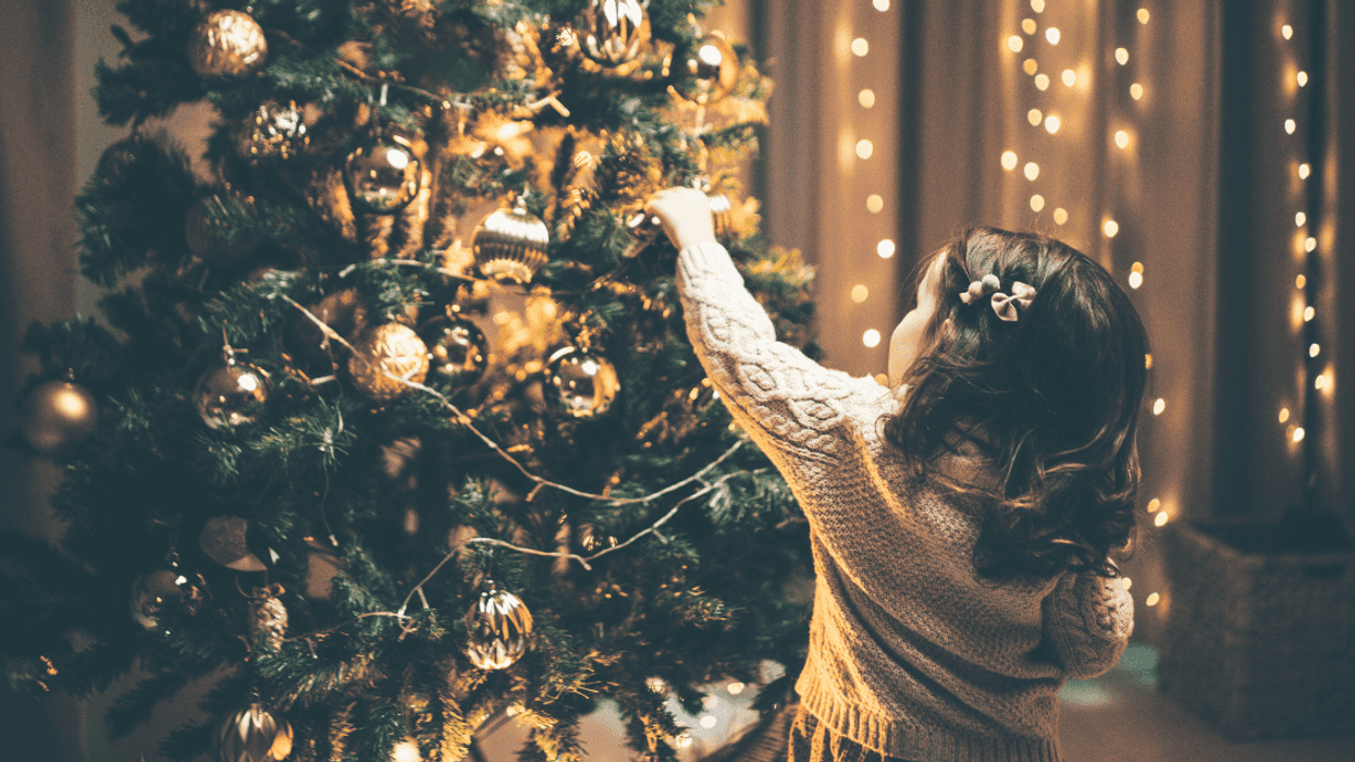 child adding decoration to Christmas tree