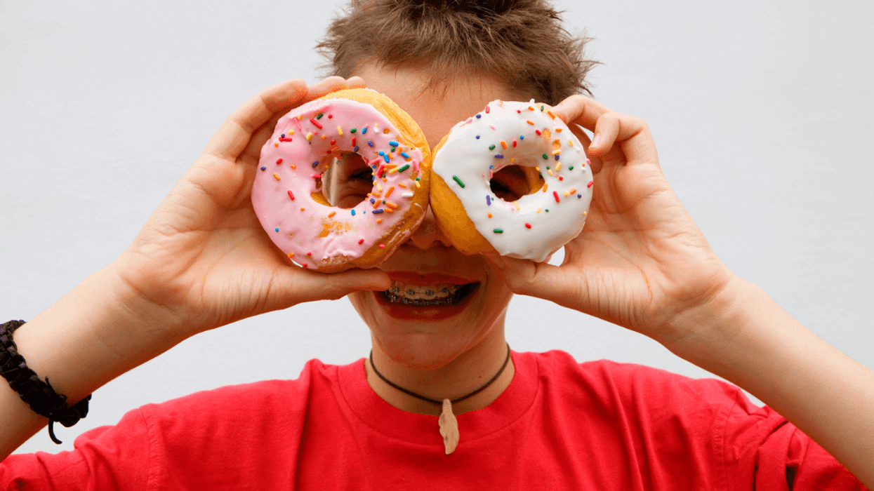 Child holding donuts over their eyes.