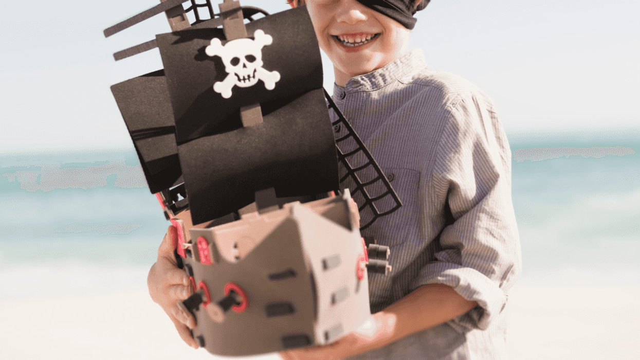 child in pirate costume holding toy ship