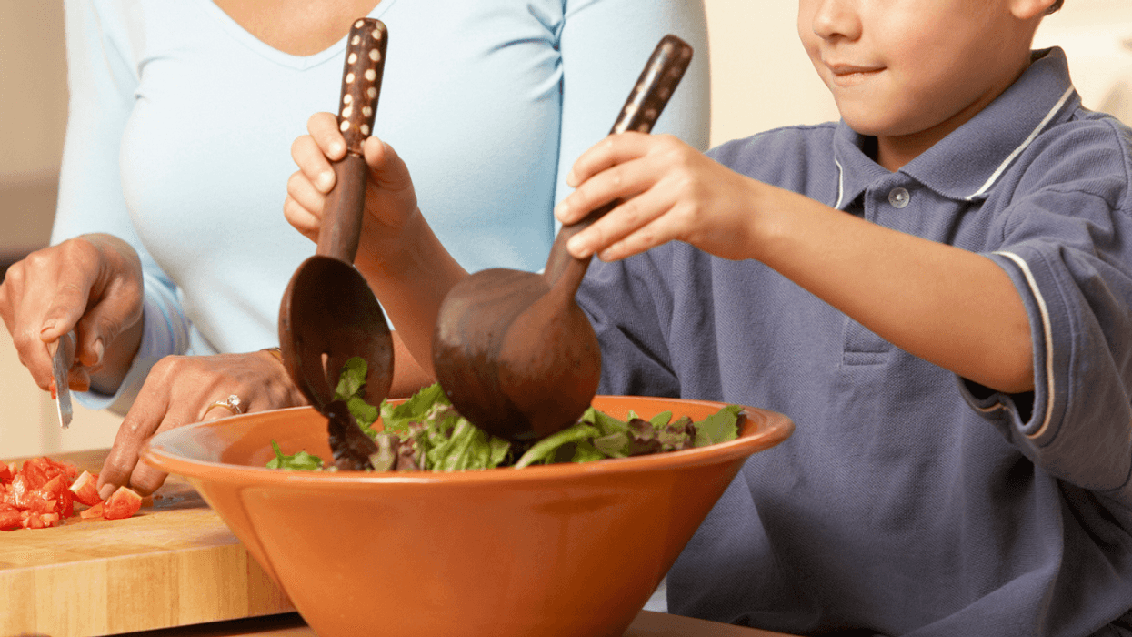 Child preparing and eating a lot of salad