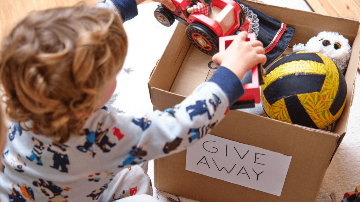 child puts toys in box to be donated
