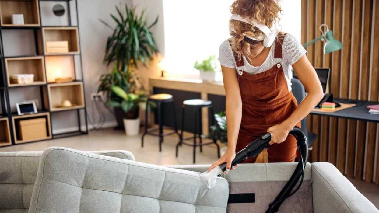 Cleaner doing deep washing of a sofa with professional equipment.