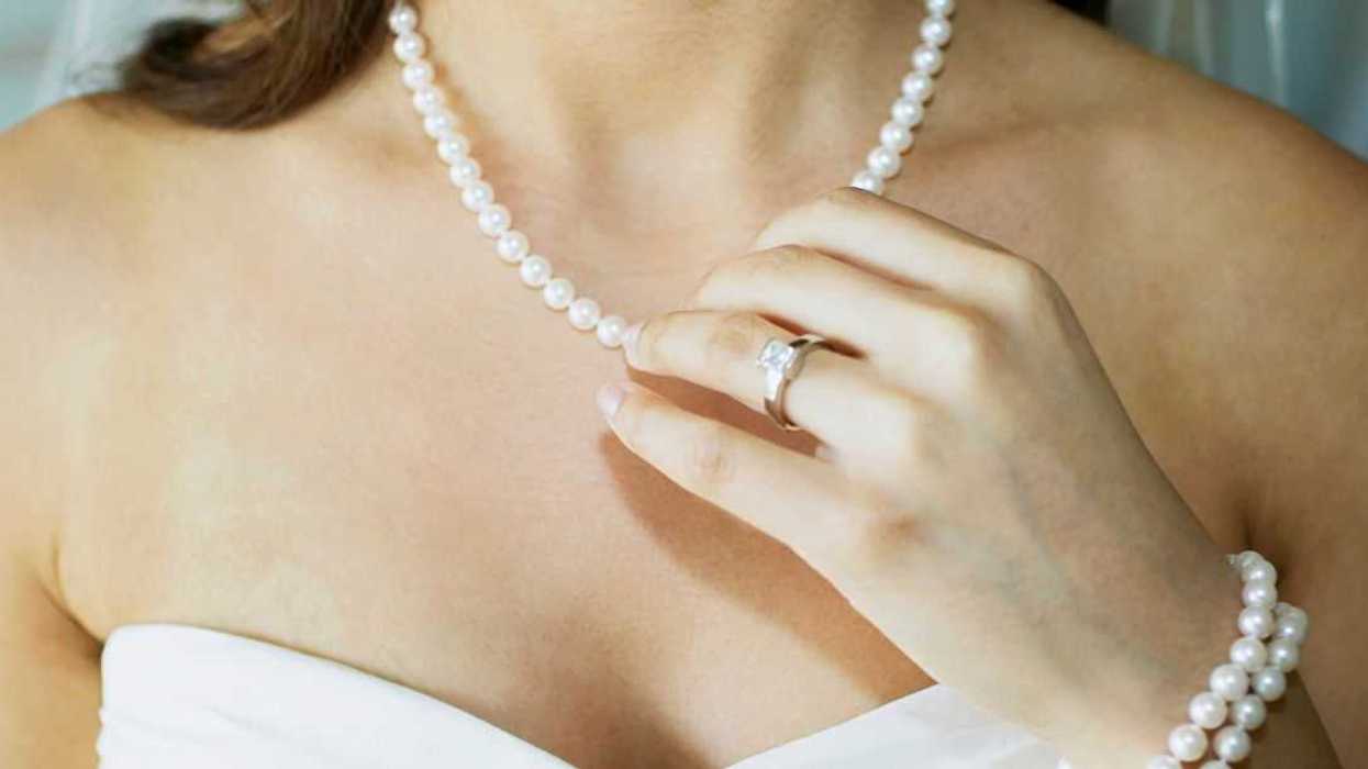 Close-up of a bride touching her pearl necklace.