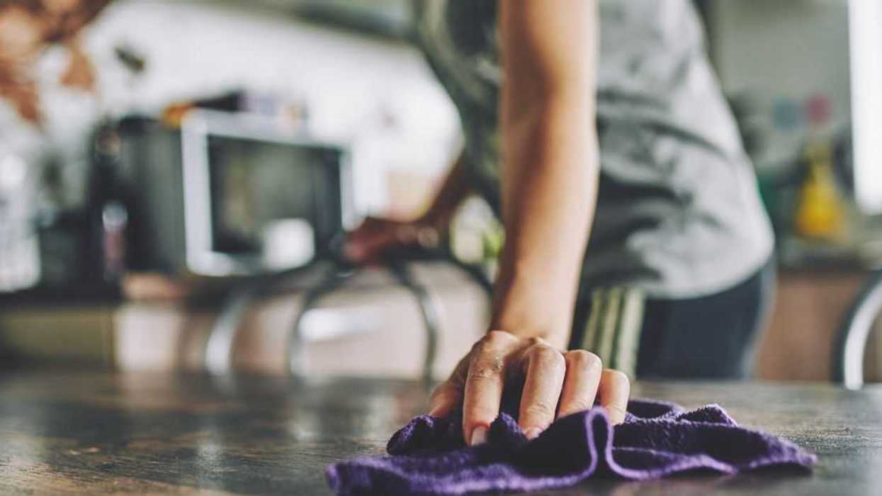 Close-up of a hand with a rag wiping a table.