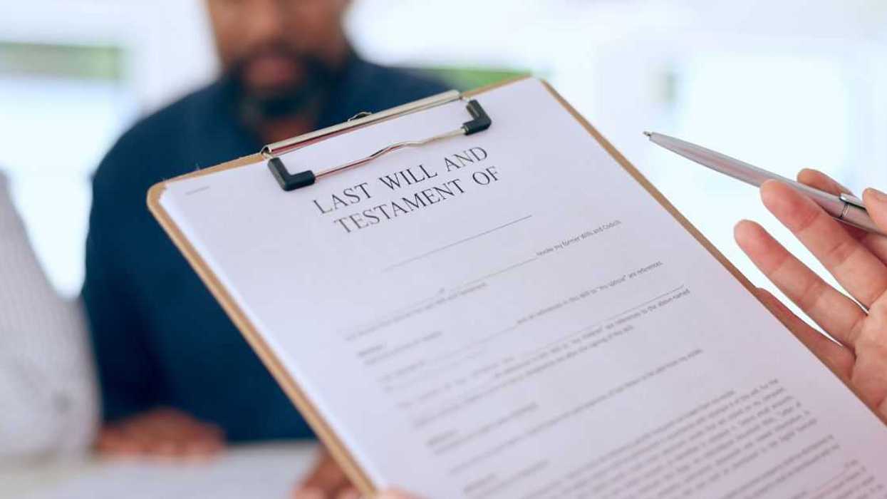 Close-up of a last will and testament about to be signed. A mature couple is blurred in the background.