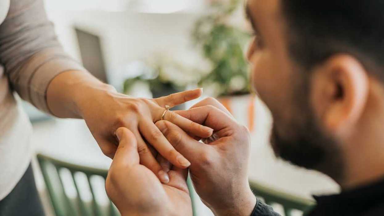 Close-up of a man, down on one knee, proposing to a woman.