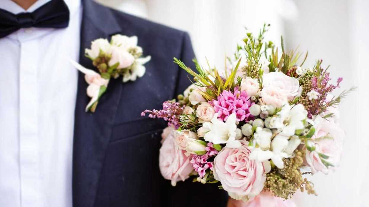 Close-up of a man in a tux holding a wedding bouquet.