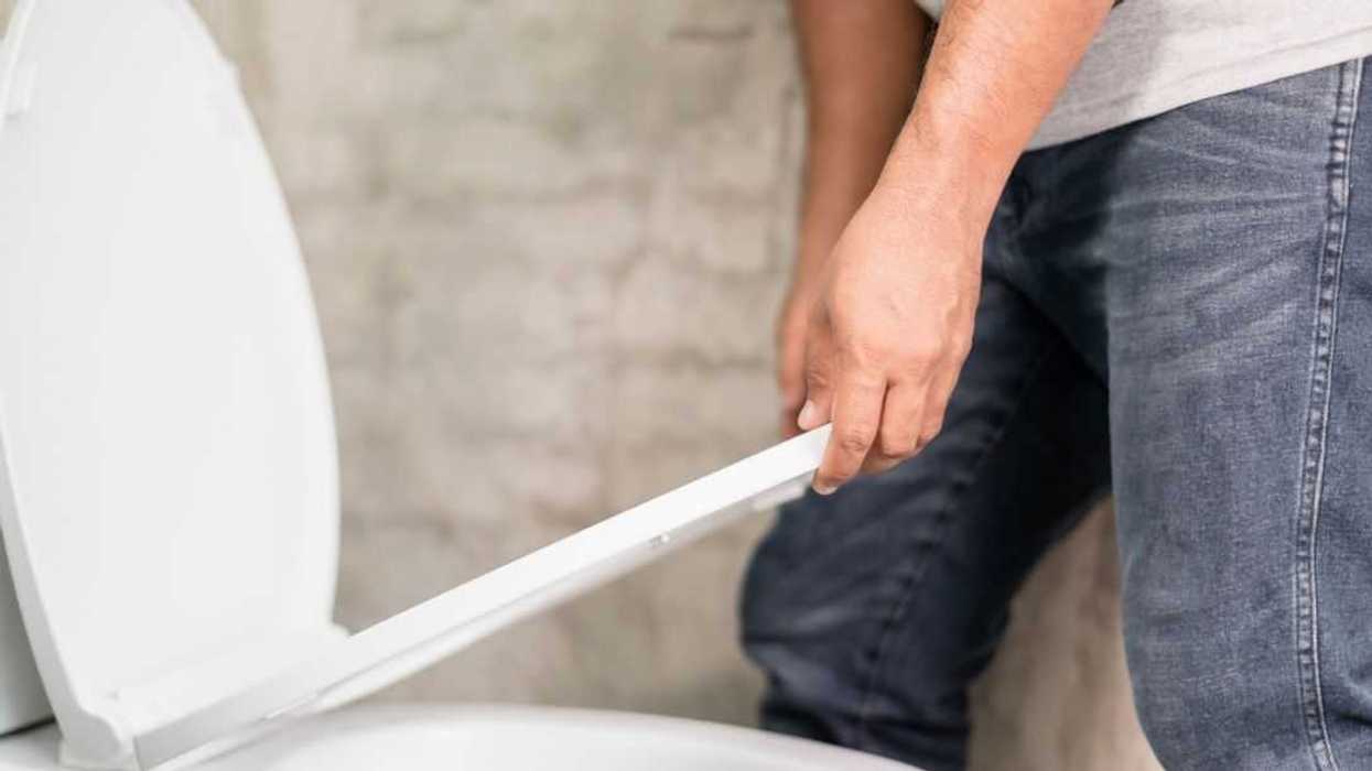 Close up of a man lifting up the toilet cover before peeing. Home sanitary concept.