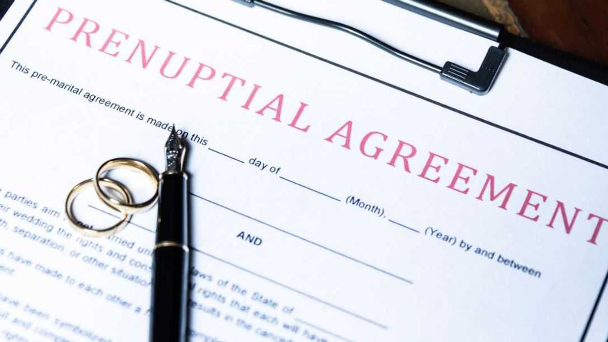 Close-up of a prenuptial agreement form with wedding rings and a fountain pen, indicating the legal aspects of marriage preparation.