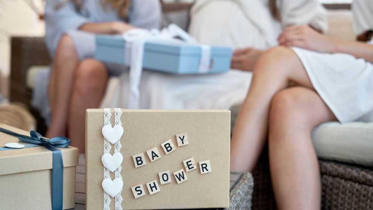 Close-up of a present marked 'baby shower,' with attendees in the background.