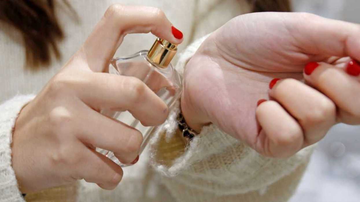 Close-up of a woman spraying perfume on wrist.