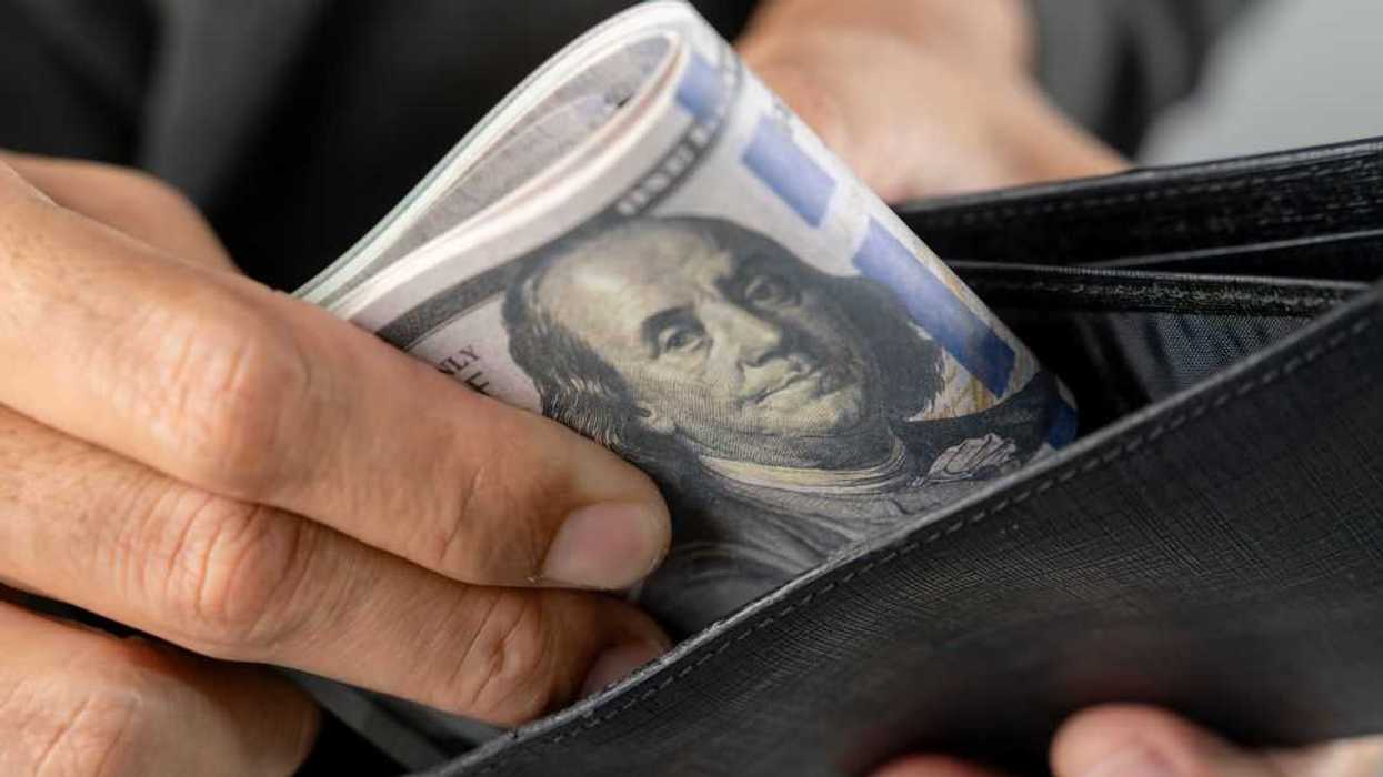 Close-up of a young man pulling cash money out of his pocket wallet, representing personal finance, daily spending, and cash payment concept.
