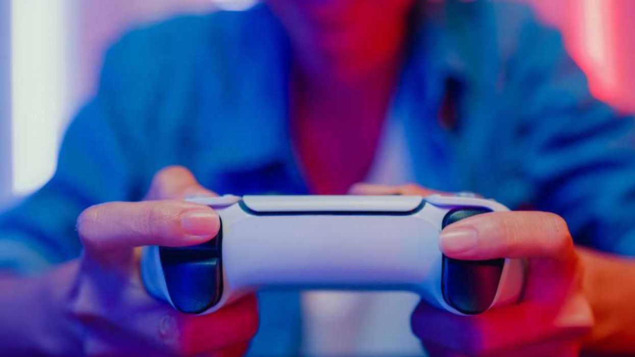 Close up of a young woman playing a video game console in neon lighted living room at home.