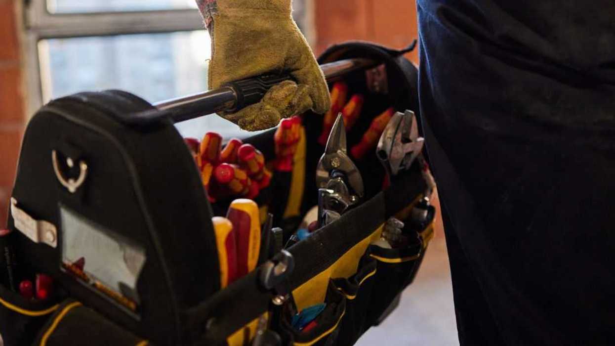 Close up of an unrecognizable electrician carrying toolbox at construction site.