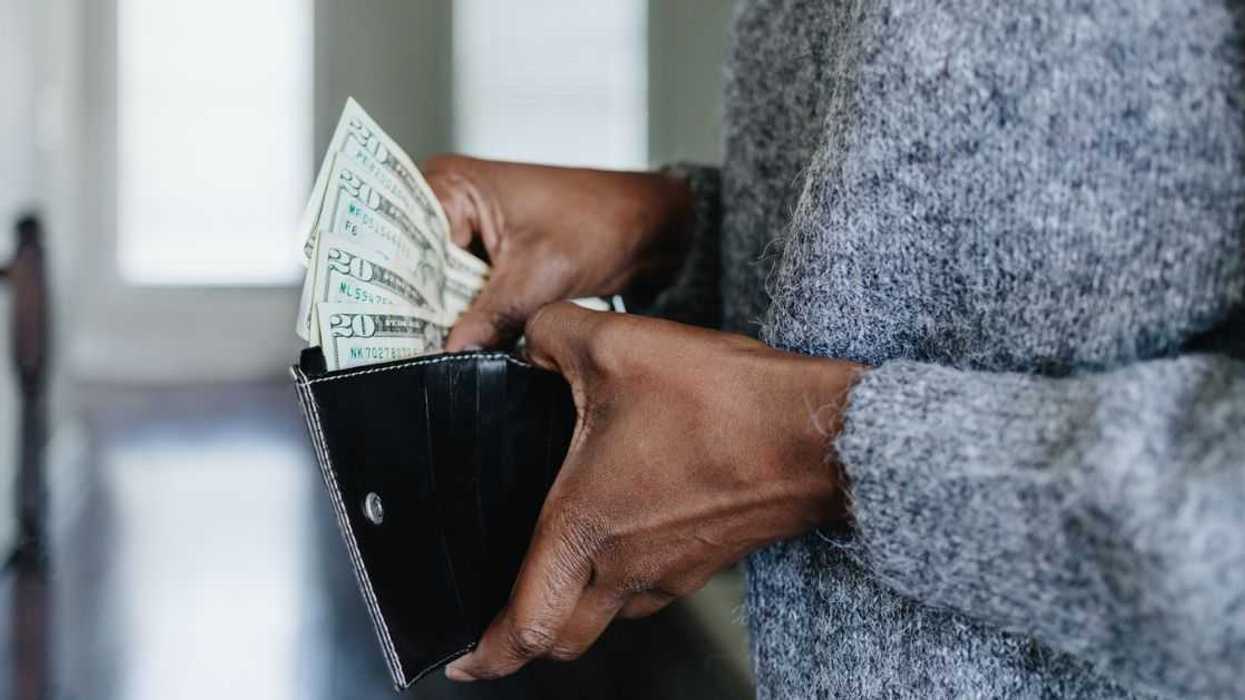 Close-up of an unrecognizable woman inserting twenty dollar bills into her wallet.