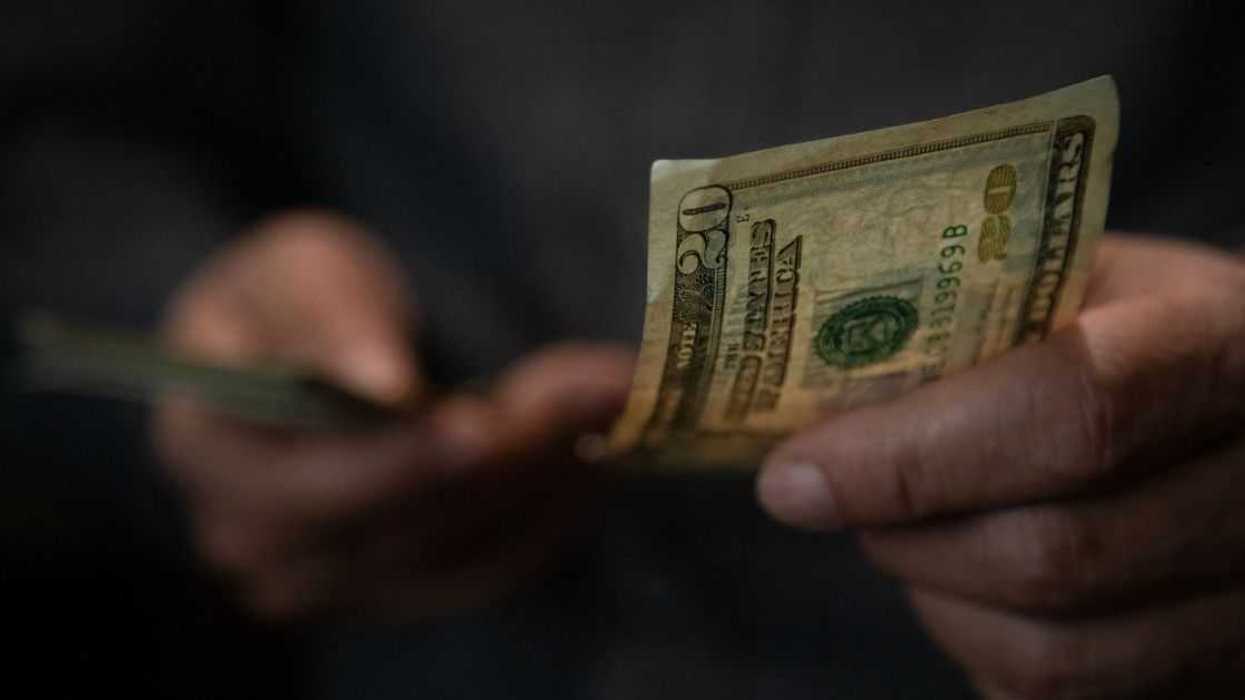 Close-up of man's hand passing a twenty dollar bill.