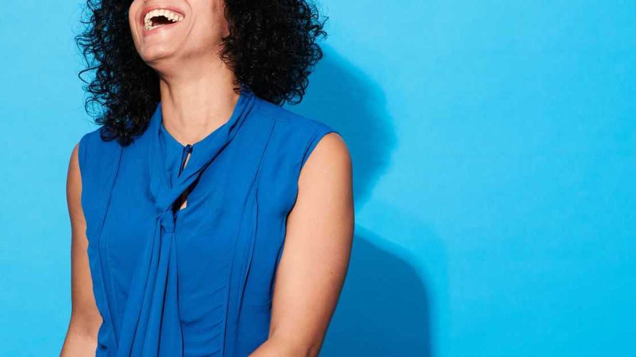 Close-up of mature woman laughing and smiling against a blue background.